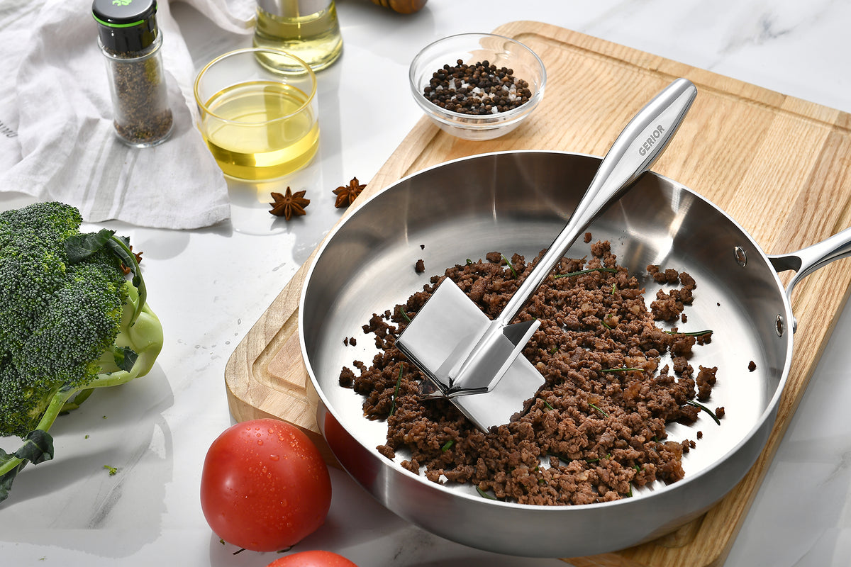 Gerior stainless steel meat chopper resting in a pan of browned ground beef
on a wooden board